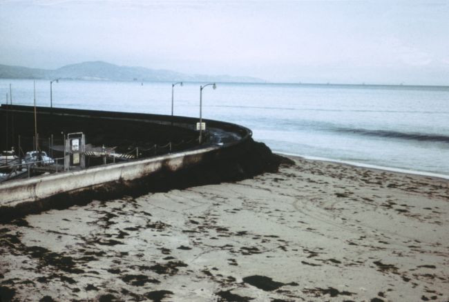 black oil piled up against a wall by the beach