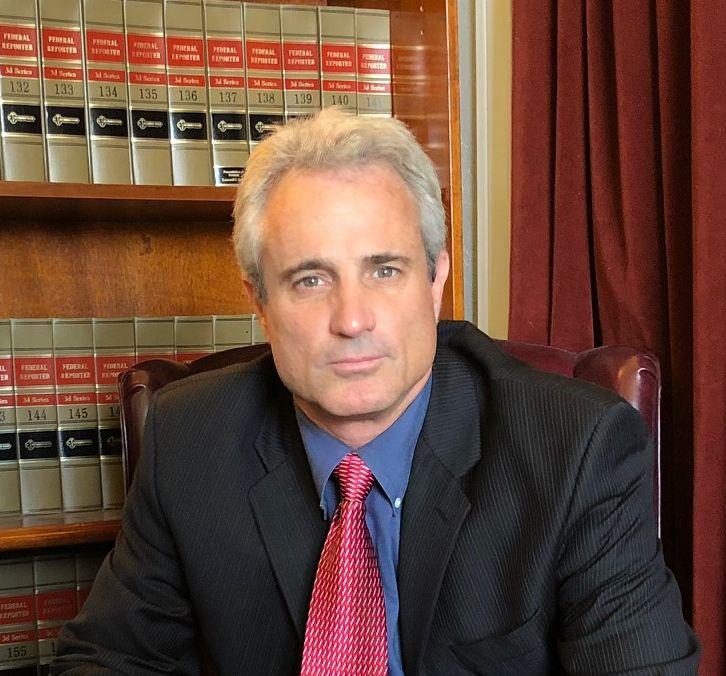 a man with slightly graying hair in a suit sits in an office