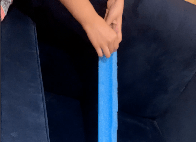 A pool noodle has been cut in half to form a roller coaster with a marble