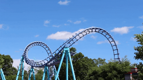 A roller coaster completes to loops against a blue sky backdrop