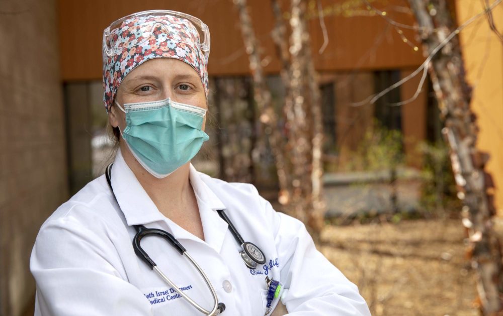 a woman in a doctor's lab coat and stethoscope, wearing a face mask