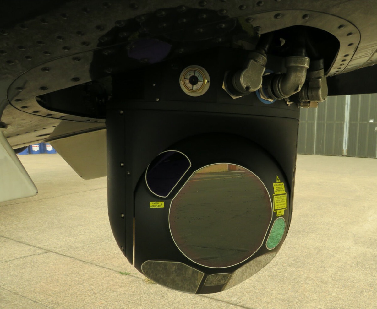 a close up of a black camera attached to a plane wing