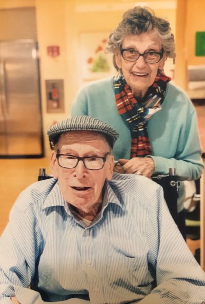 a married couple, an older man in a wheel chair and an older women standing behind him.