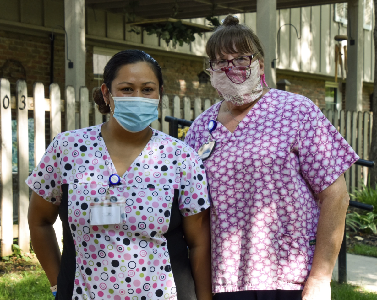 two nurses in masks standing outside a nursing home