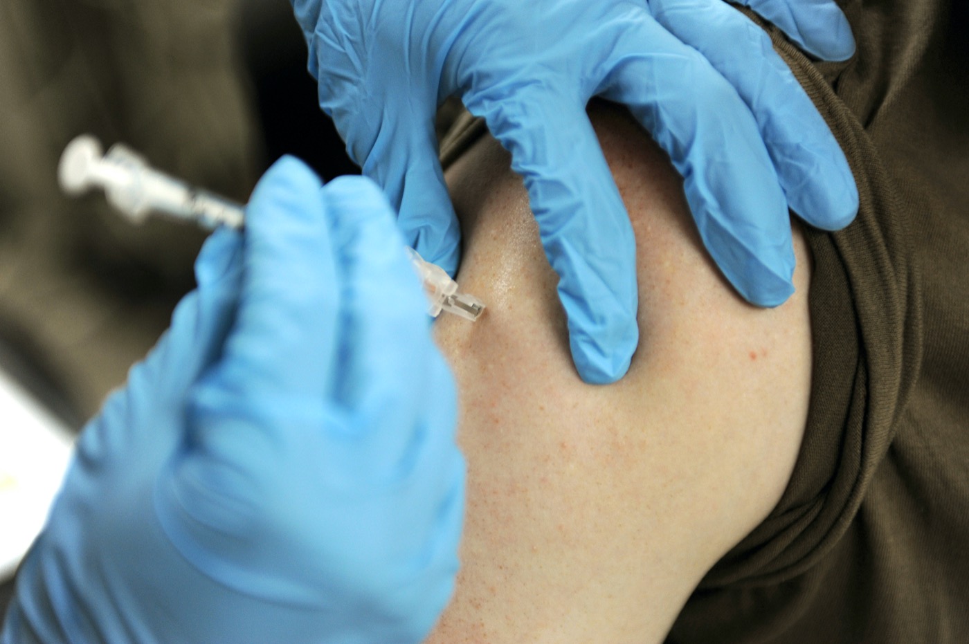 a person with gloves on administers a shot in someone's shoulder