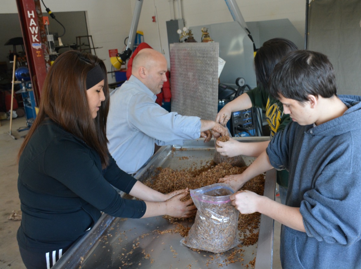 four people putting brown material into bags. 