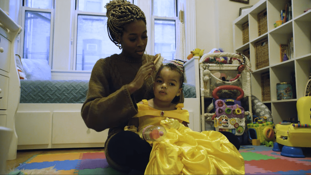 a black woman and combs her daughter's hair