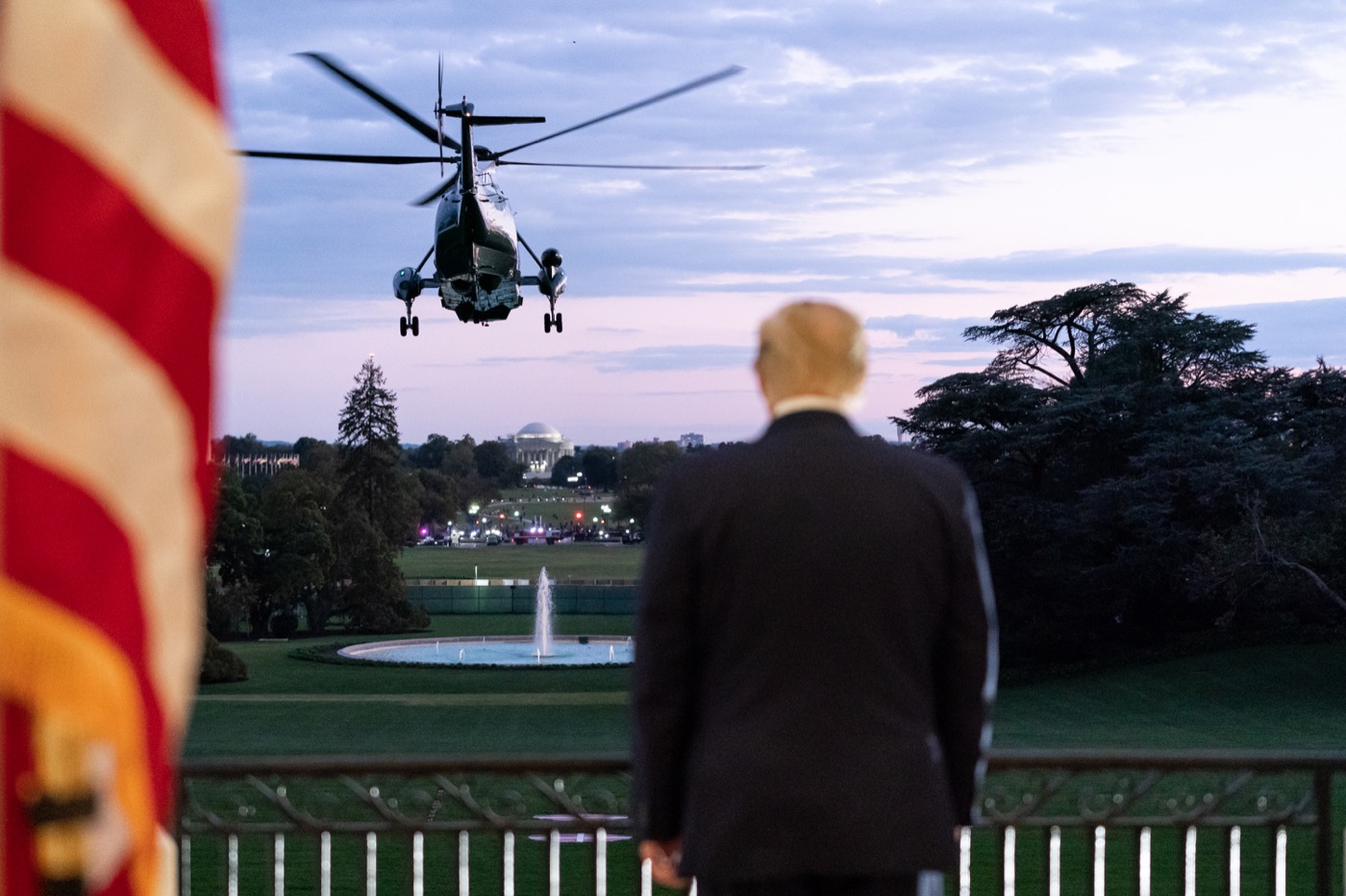 trump from behind on the balcony of the white house as he watches a helicopter flies away