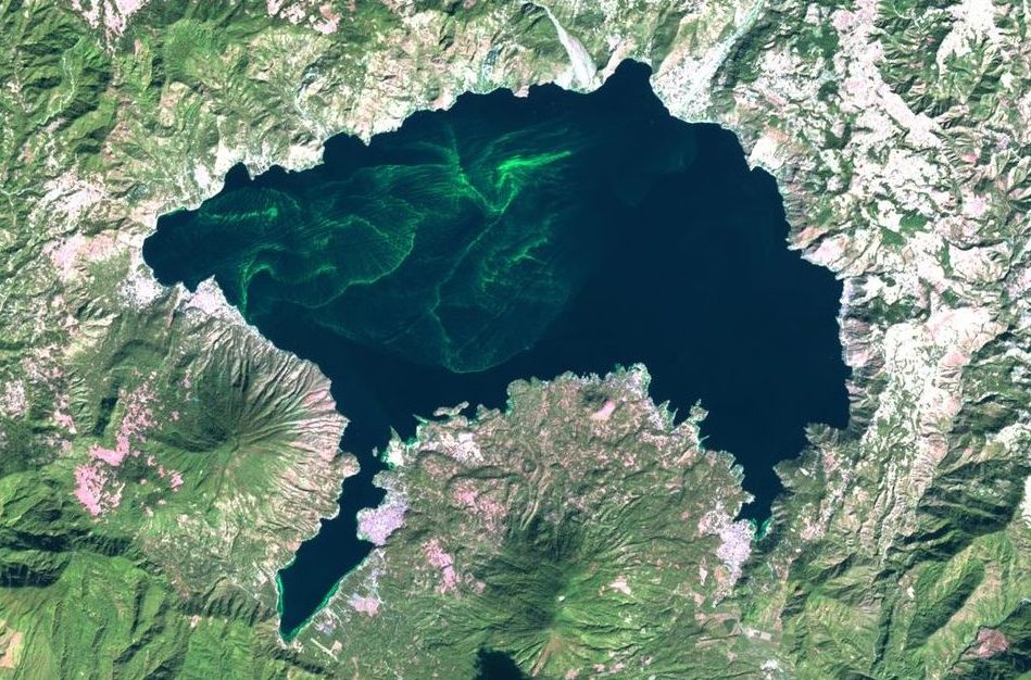 a satellite image of a lake with small waves of green algae