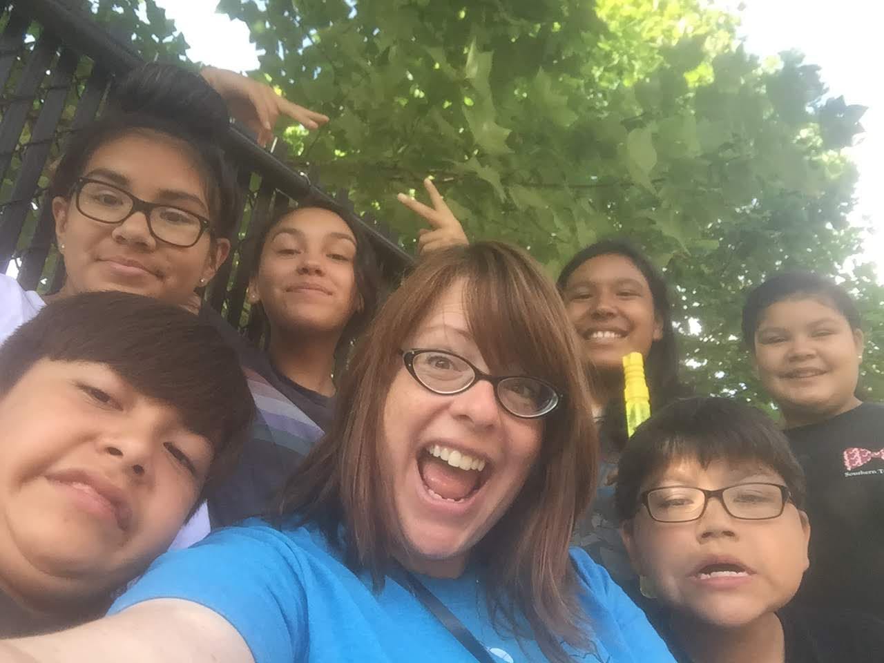 an Indigenous woman with a group of kids posing for the camera