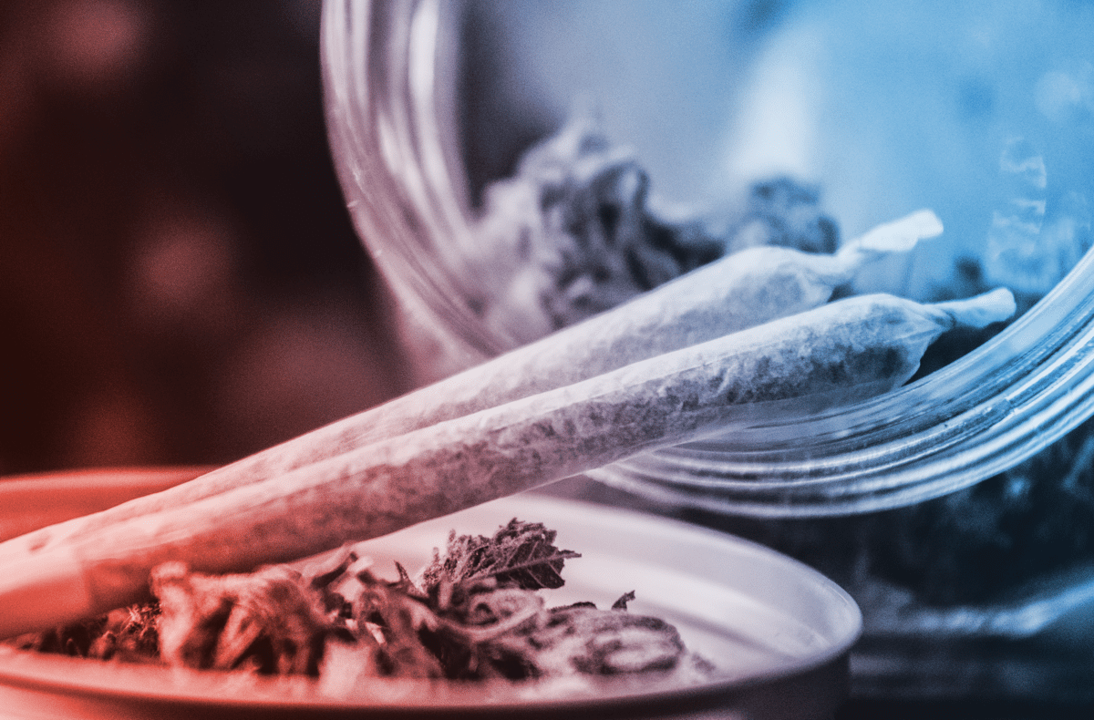 a glass jar filled with two blunts and marijuana buds