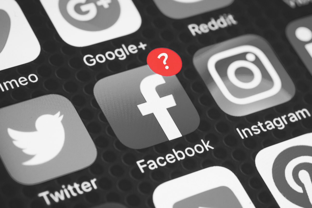 a black and white image social media apps on a phone screen, with a close up on twitter, instagram, and facebook. the facebook app has a red notification with a question mark in it