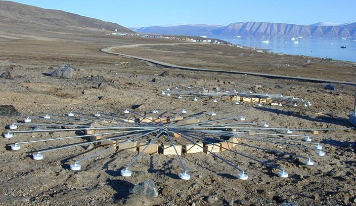 Infrasound arrays at infrasound station IS18, Qaanaaq, Greenland. Ground overlooking water with a circular arrangement of sensors all hooked together in the center used to detect infrasound.