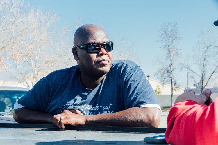 an african american man wearing sunglasses and leaning on the side of a truck