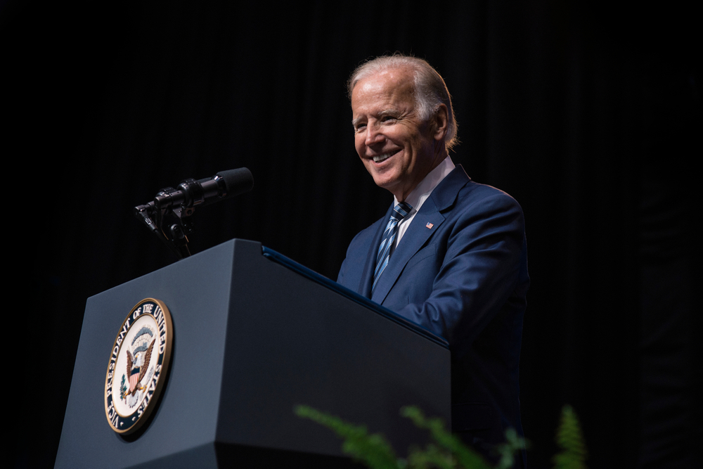 biden smiling standing at a podium