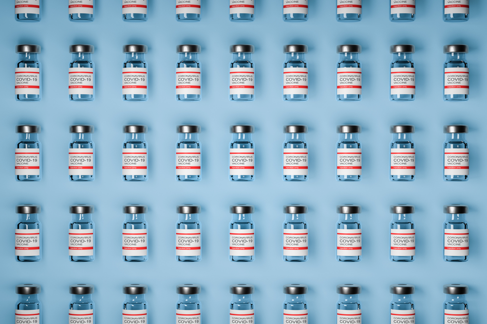 pattern of vaccine bottles against covid-19 with injection fluid. Coronavirus vaccine on Blue background