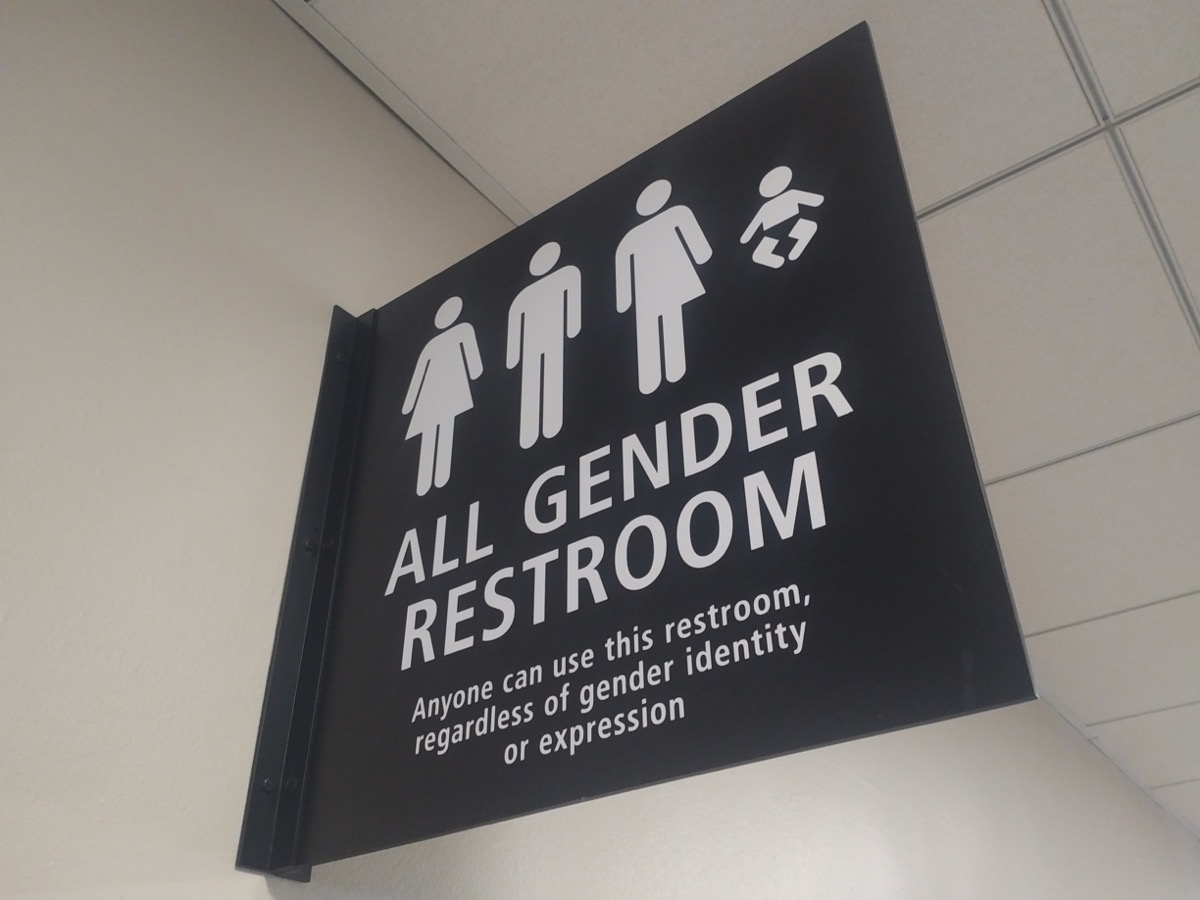 a black sign with symbols expressing various gender identities, including female, male, transgender, nonbinary, and also children. the sign reads "all gender restroom: anyone can use this restroom regardless of gender identity or expression."