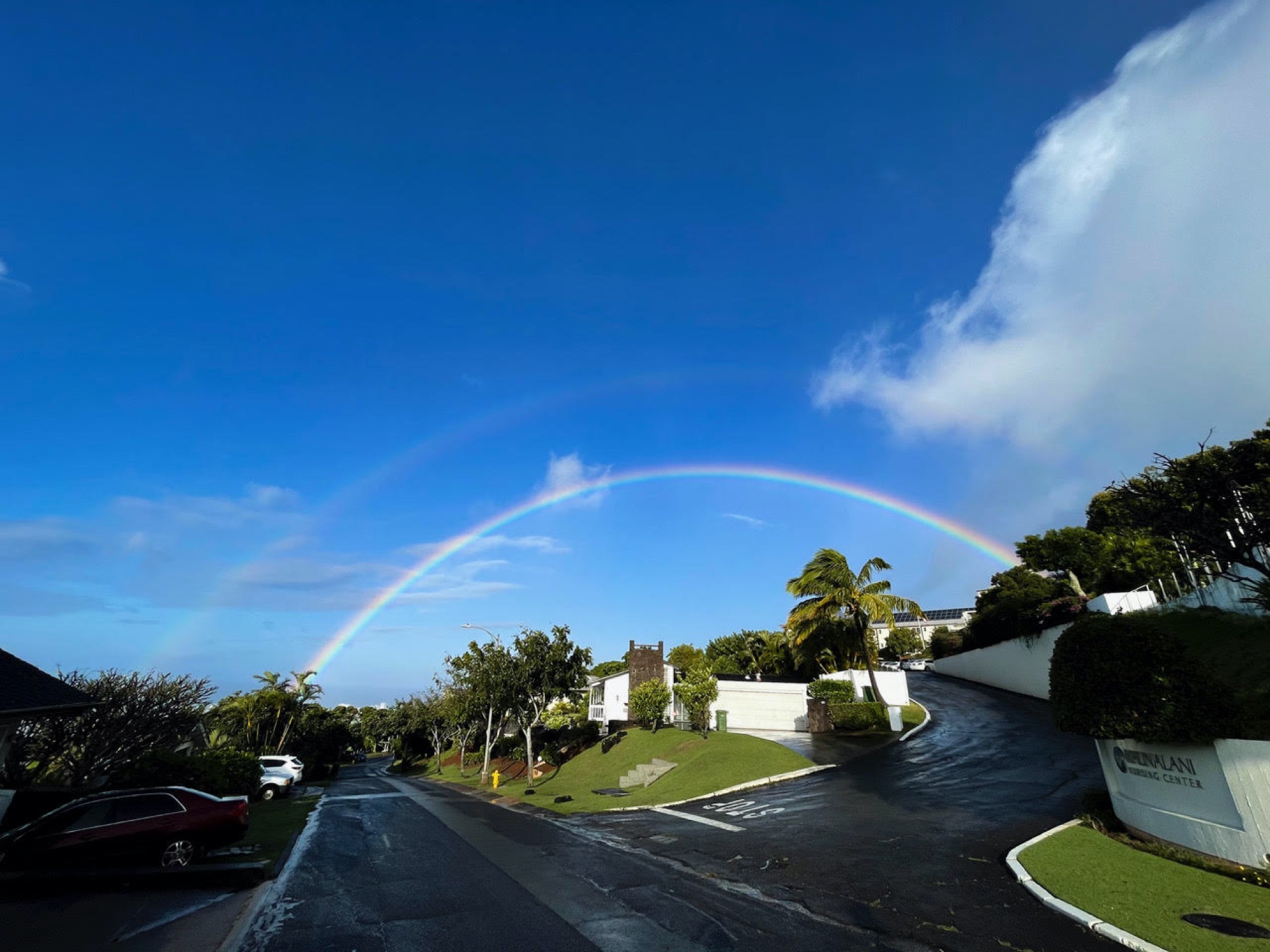 a clear blue sky with some small cloud coverage. arching across the center of the sky is a bright double rainbow