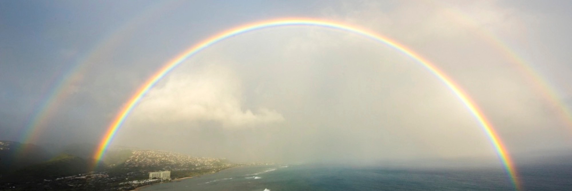a double rainbow over the coastline of an island