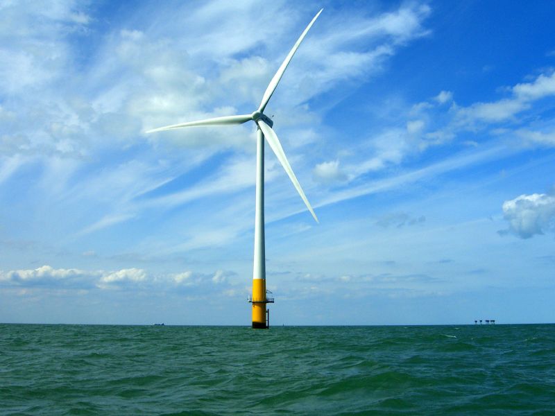 a wind turbine in the ocean on a blue sky day