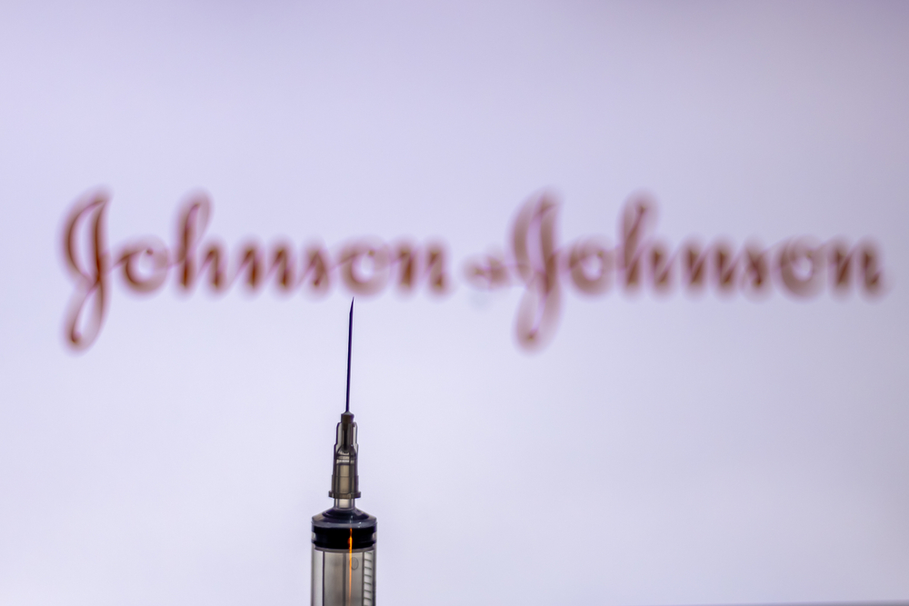 a needle in the foreground and the johnson and johnson logo in the background