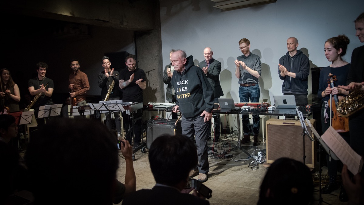 an older man with a mustache stands in the middle of an orchestra at a show