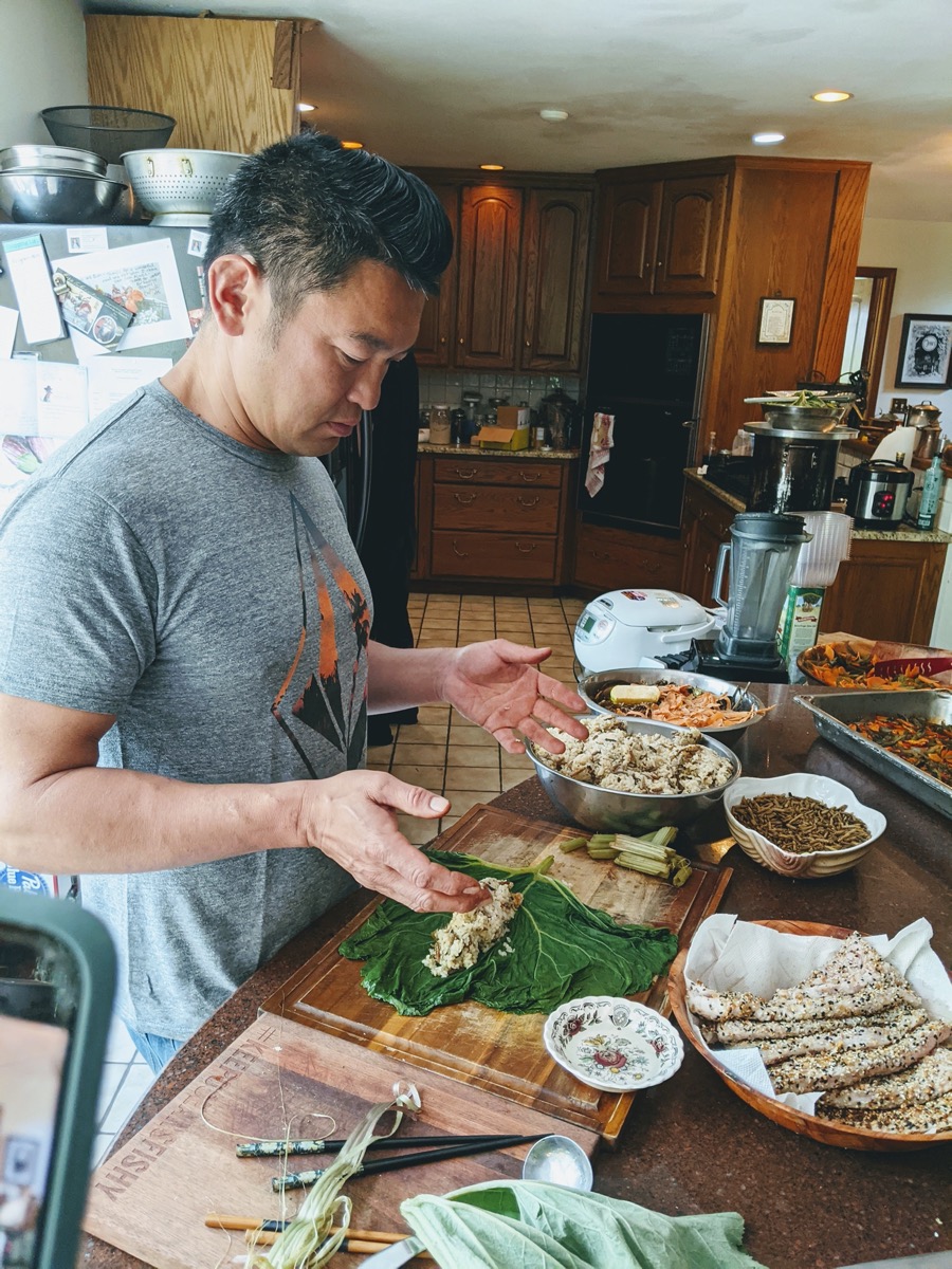 an asian man making sushi with cicadas in a kitchen