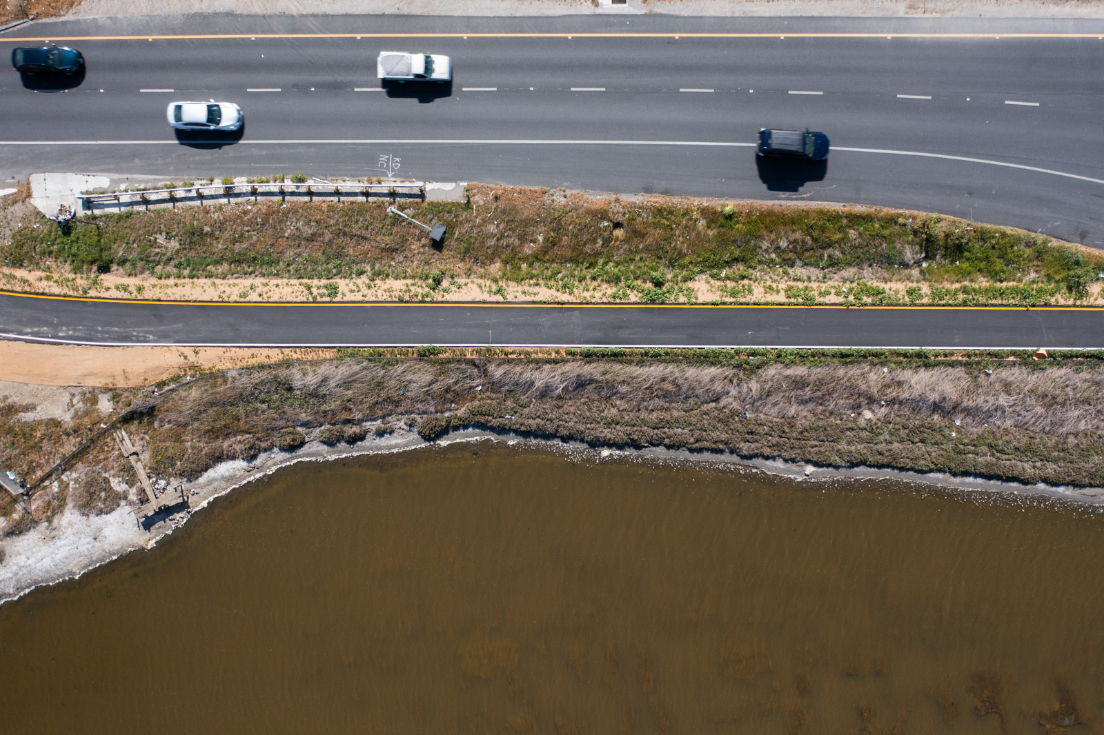 an aerial view of a bridge with a road with cars driving across water