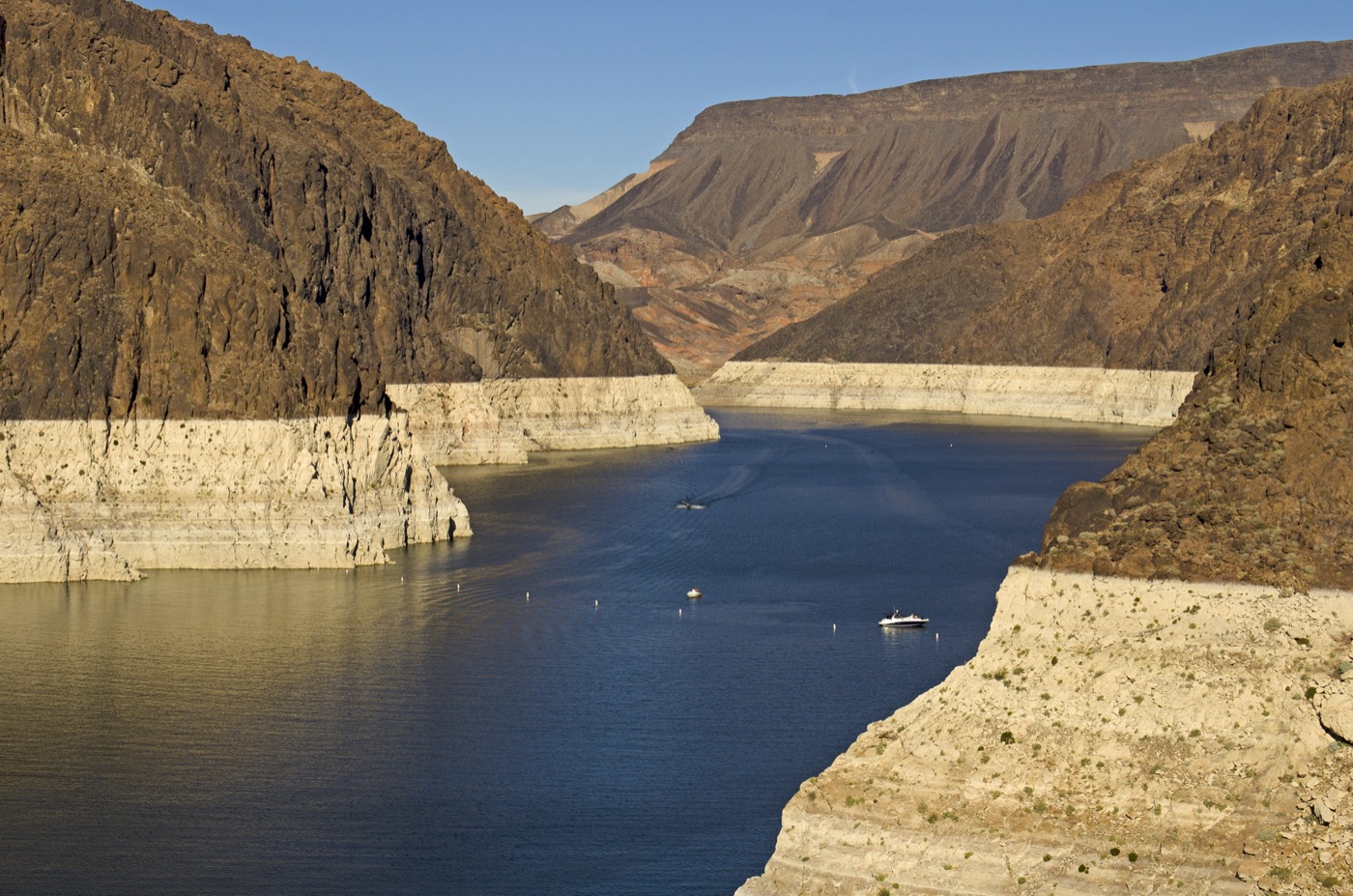 a picture of lake with mountains surrounding it, with a consistent ring of whiter rock above the lake where the water line used to be