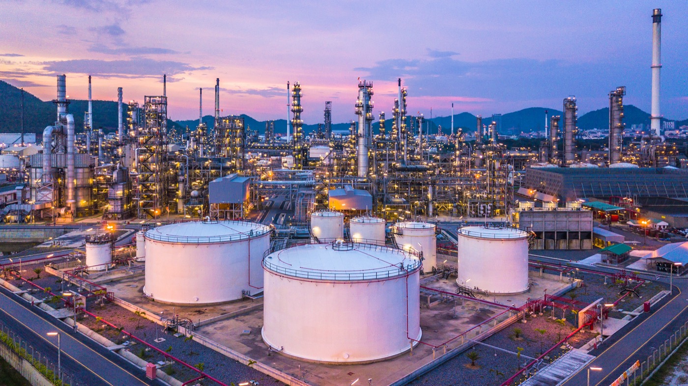 aerial view of a sprawling oil refinery with many round large tanks and myriad pipes