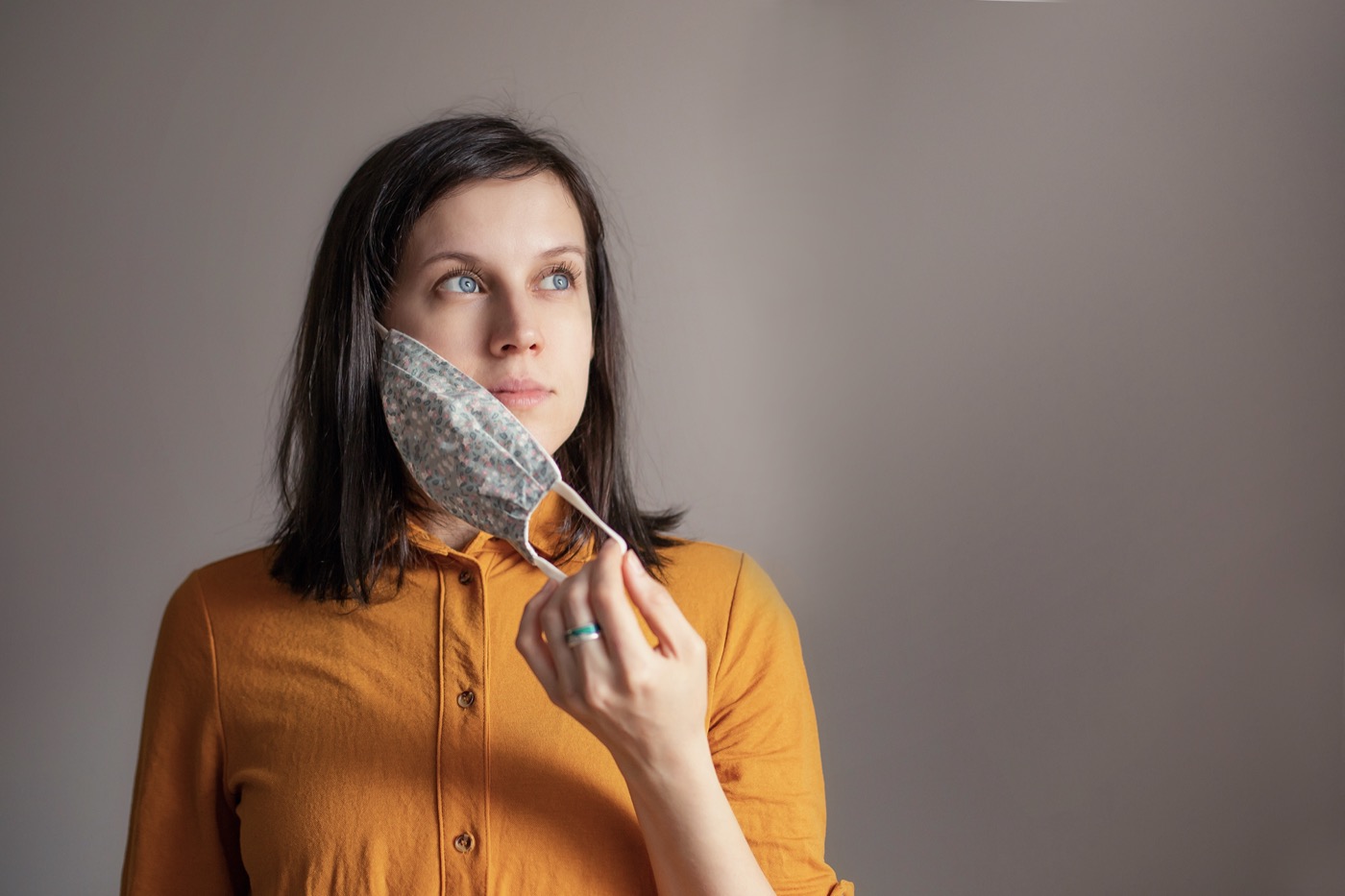 a white woman looking off screen taking off her mask