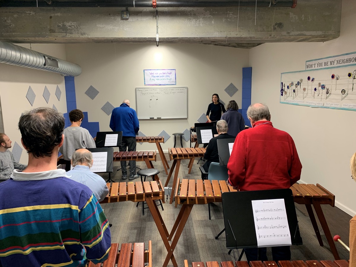 a class of elderly people playing xylophones with an instructor at the front