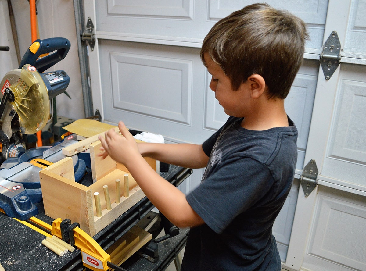 Young boy working on building a puzzle box out of wood.