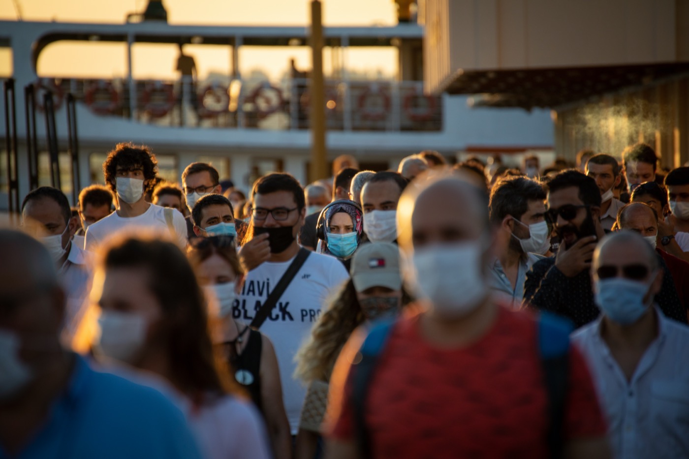 a crowd of people at sunset mostly wearing masks
