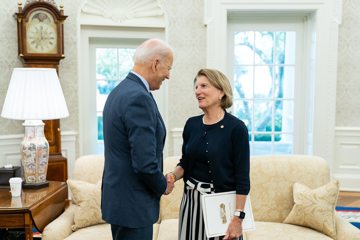 a man and a woman shake hands in an office of the white house