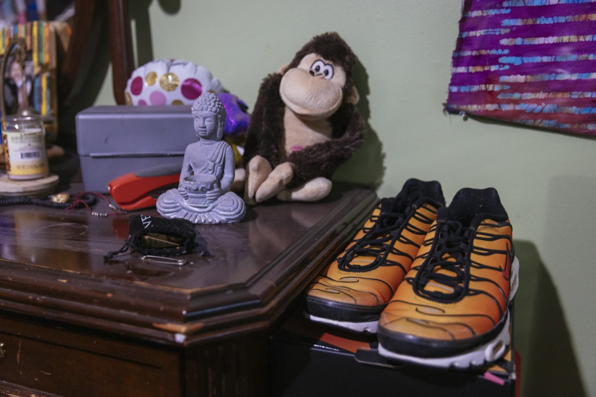 a collection of items on a dresser, including a monkey stuffed animal, purple buddha statue, and yellow running shoes