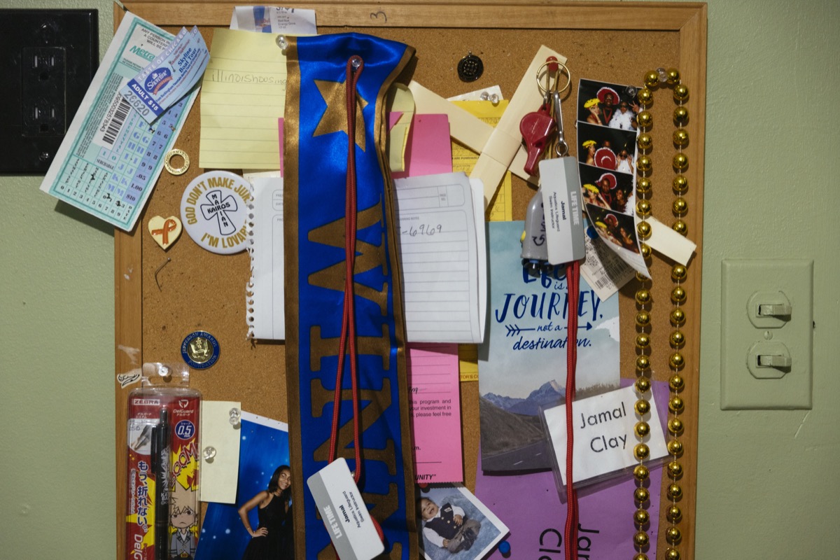 a cork board on a wall with a variety of pinned mementos such as a school ribbon, beads, pins, cards, and aspirational notes