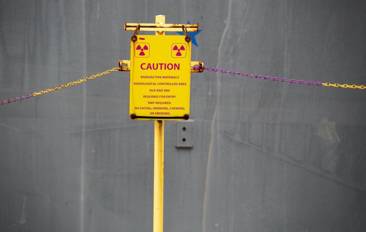 a yellow caution sign that reads "radioactive materials radiological controlled area DLR and SRD required for entry RWP required no eating drinking chewing or smoking" 