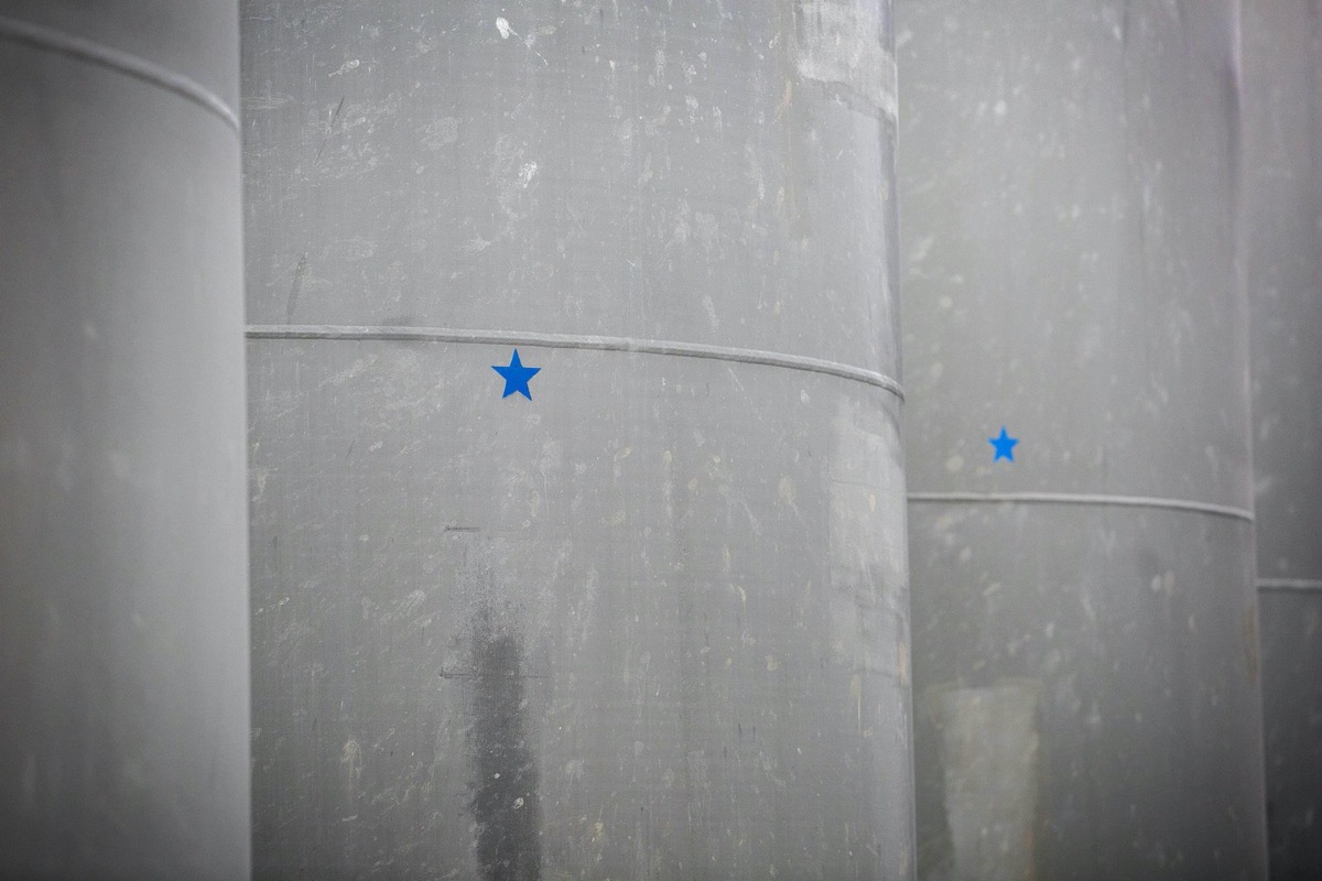 a close up on large gray cylinder casks, each with blue stars