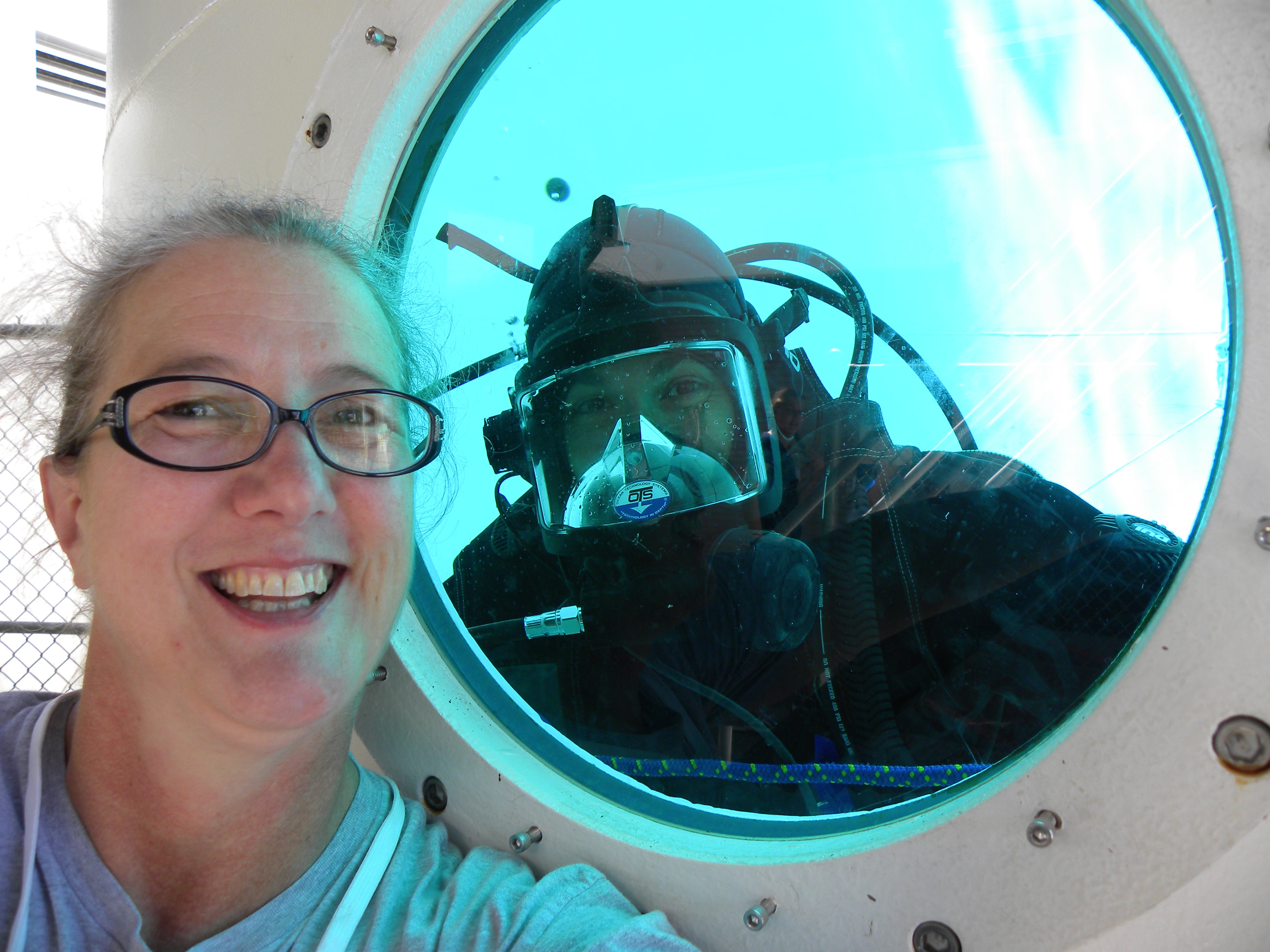 Diver in full scuba gear that the window of a training tank and educator Turtle Haste outside, selfie