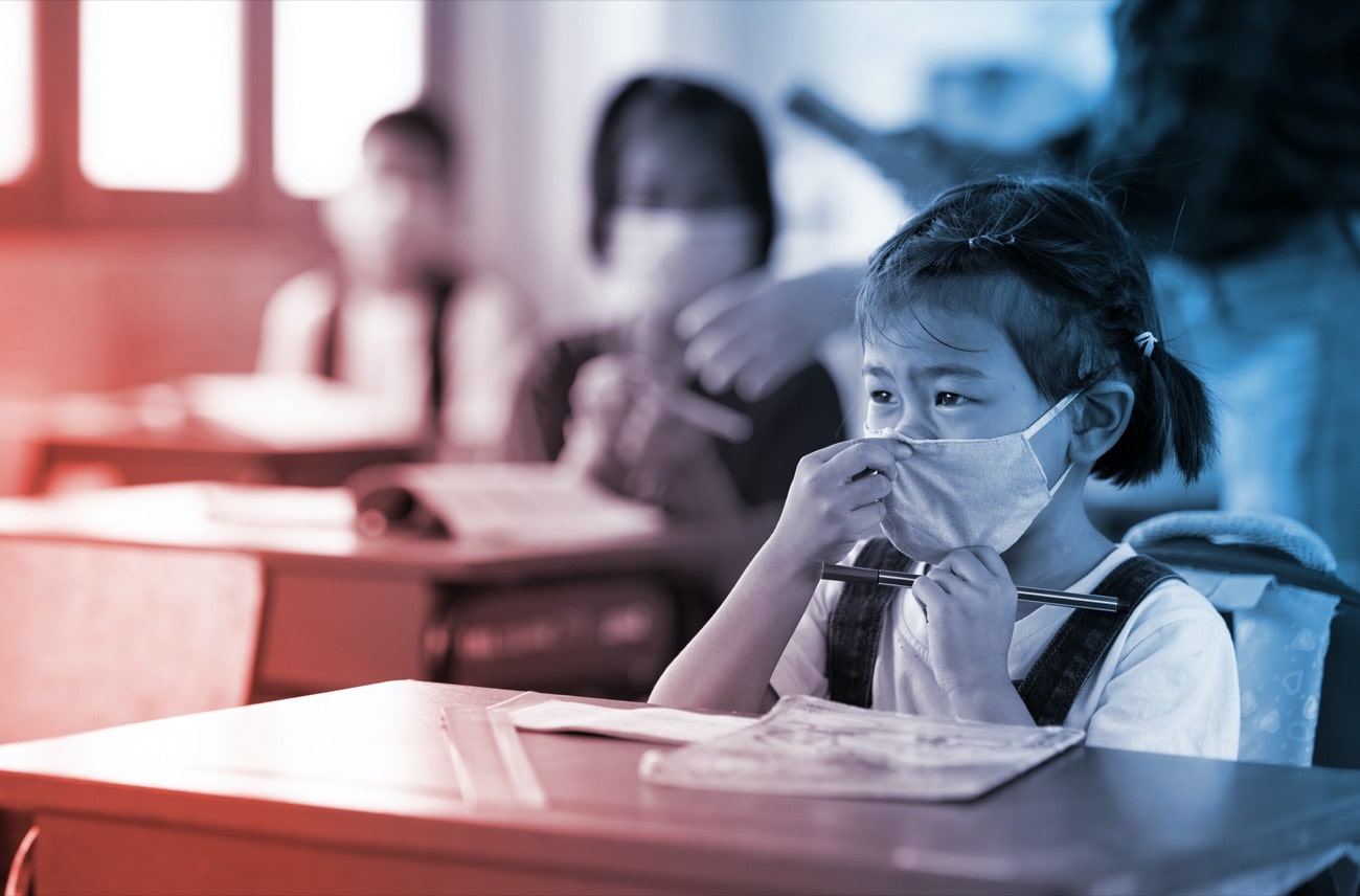 a young asian girl adjusts her mask with other students behind her and a teacher, all wearing masks