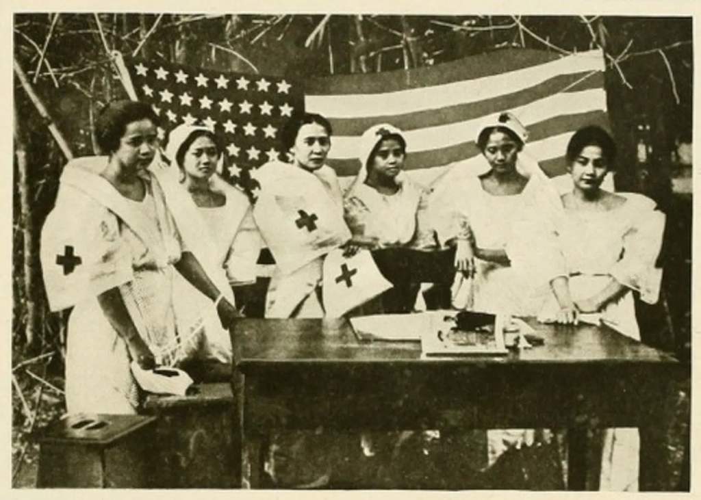 an old black and white photo of six filipino nurses in nurses uniforms standing behind a desk and in front of an american flag