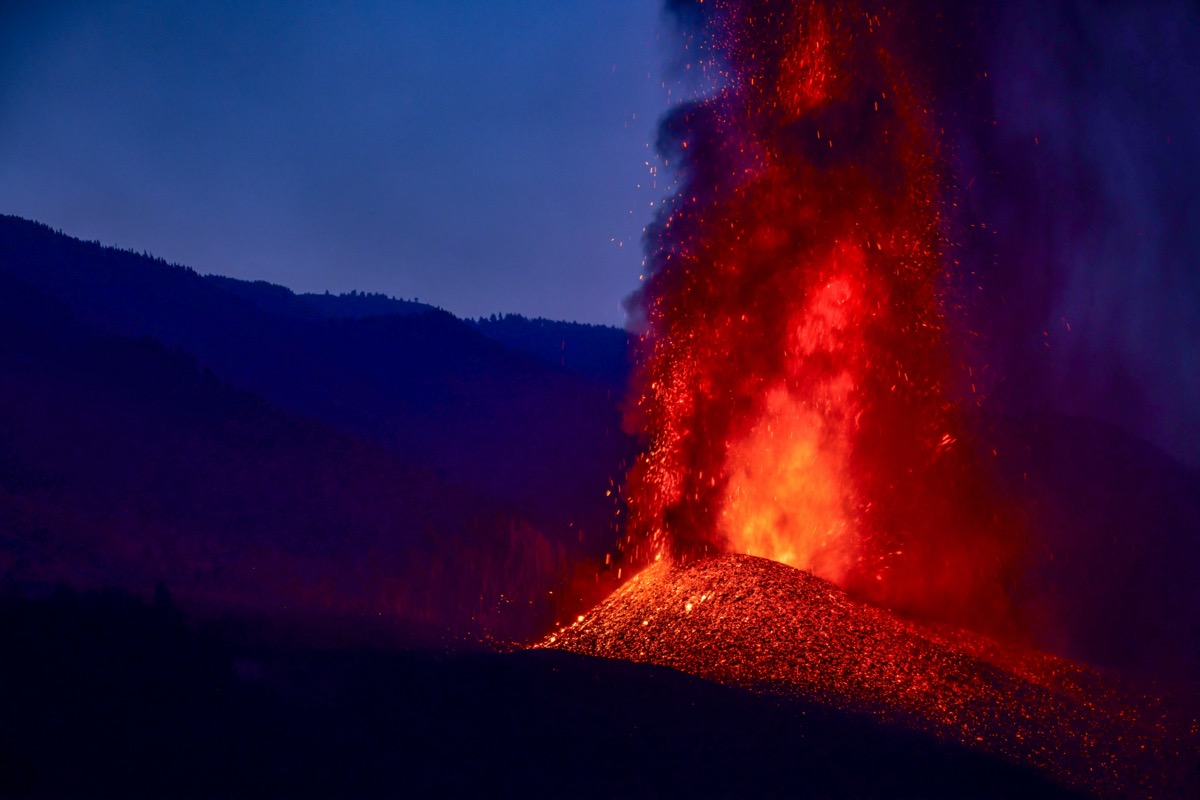 a volcano spewing bright red lava at night