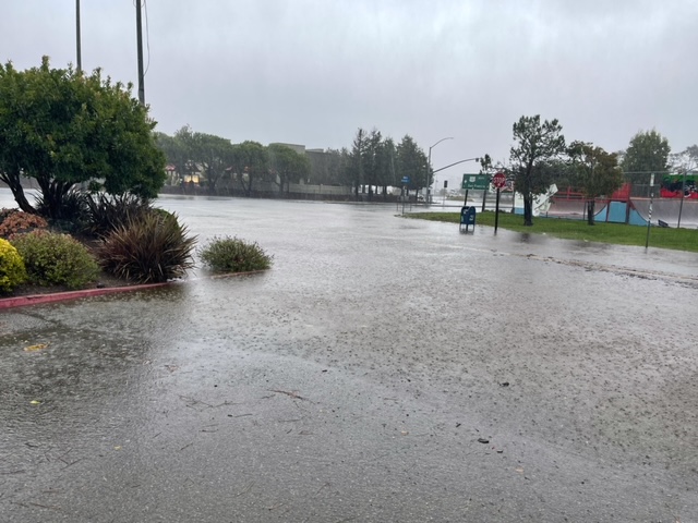 heavy rainfall on a street with a playground in the distance