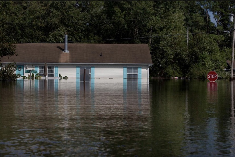 a street completely flooded with water with the water level rising high up above the floor of a house