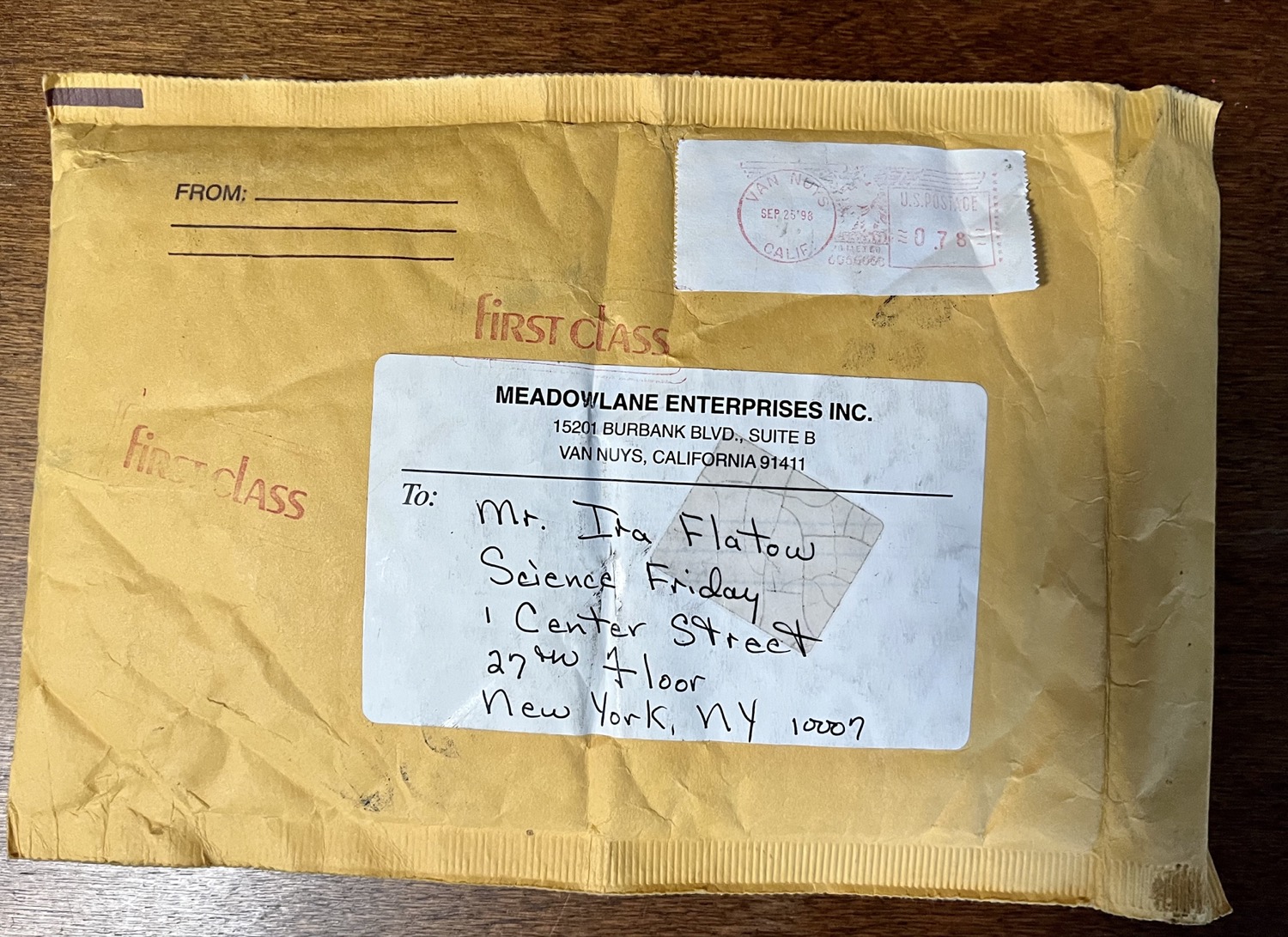 a manilla package that says "to mr. ira flatow, since friday, 1 center street, 27th floor, new york, ny 10007, from meadowlane enterprises inc., 15201 burbank blvd. suite b, van nuys, california 91411