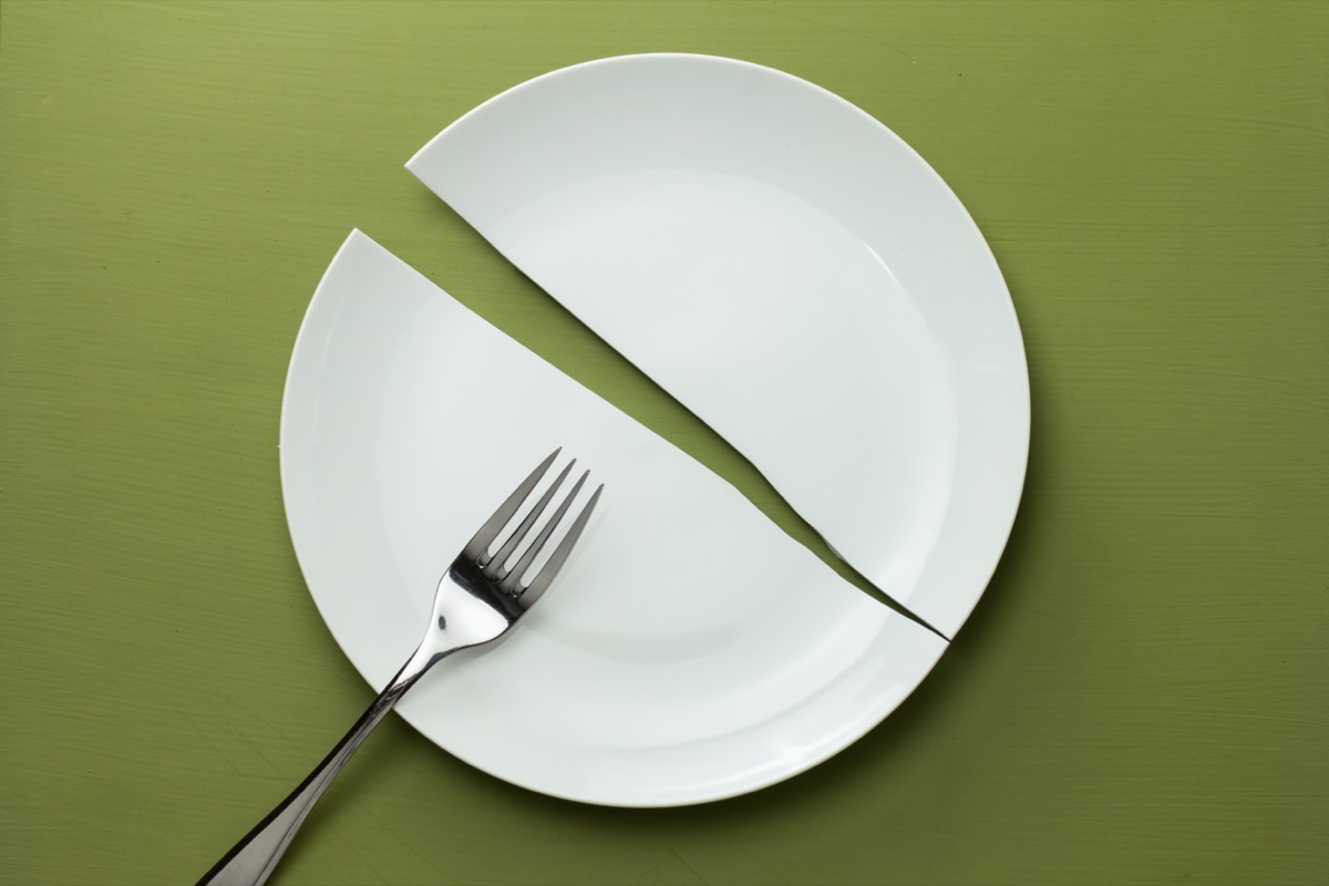 a white plate broken in half with a fork on it on a green background
