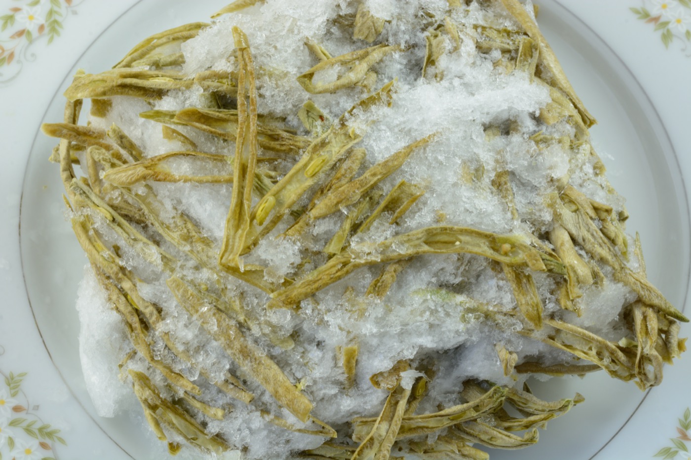 a plate of pale green beans with ice all over it