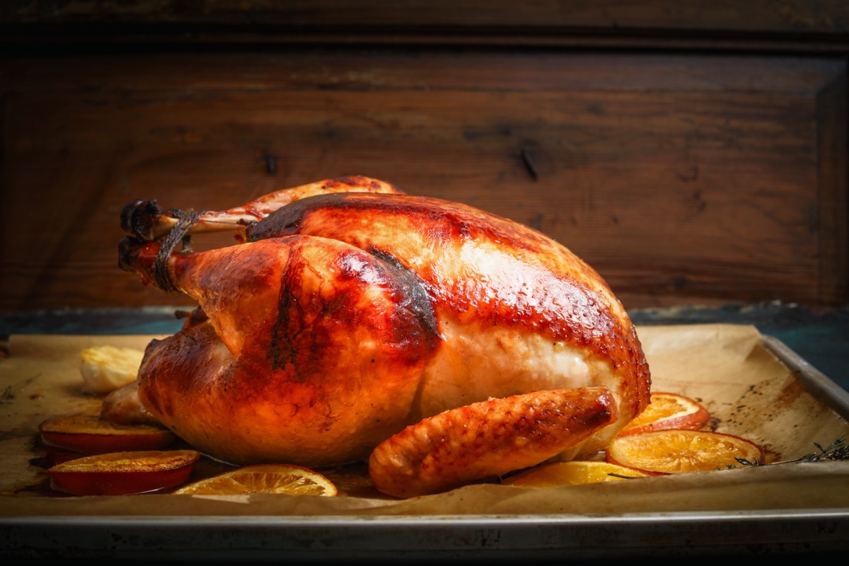 Roast whole turkey or chicken over wooden background, side view