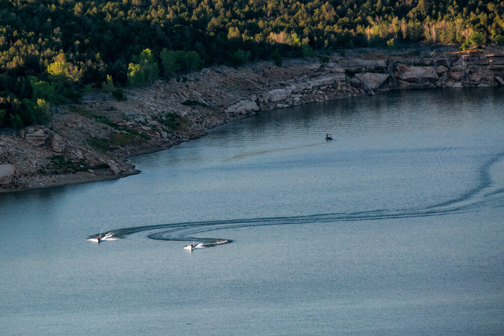 an arial view of a river with three ducks swimming in it, leaving water trails behind them